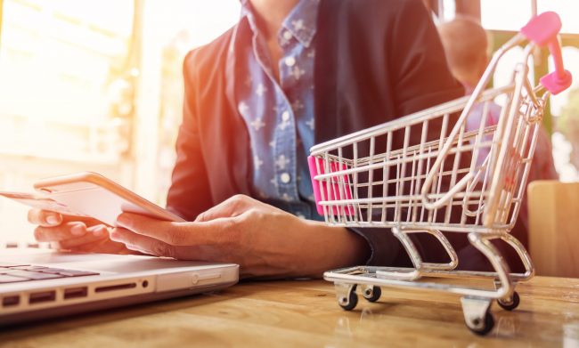Cropped image of woman inputting card information and key on phone or laptop while shopping online